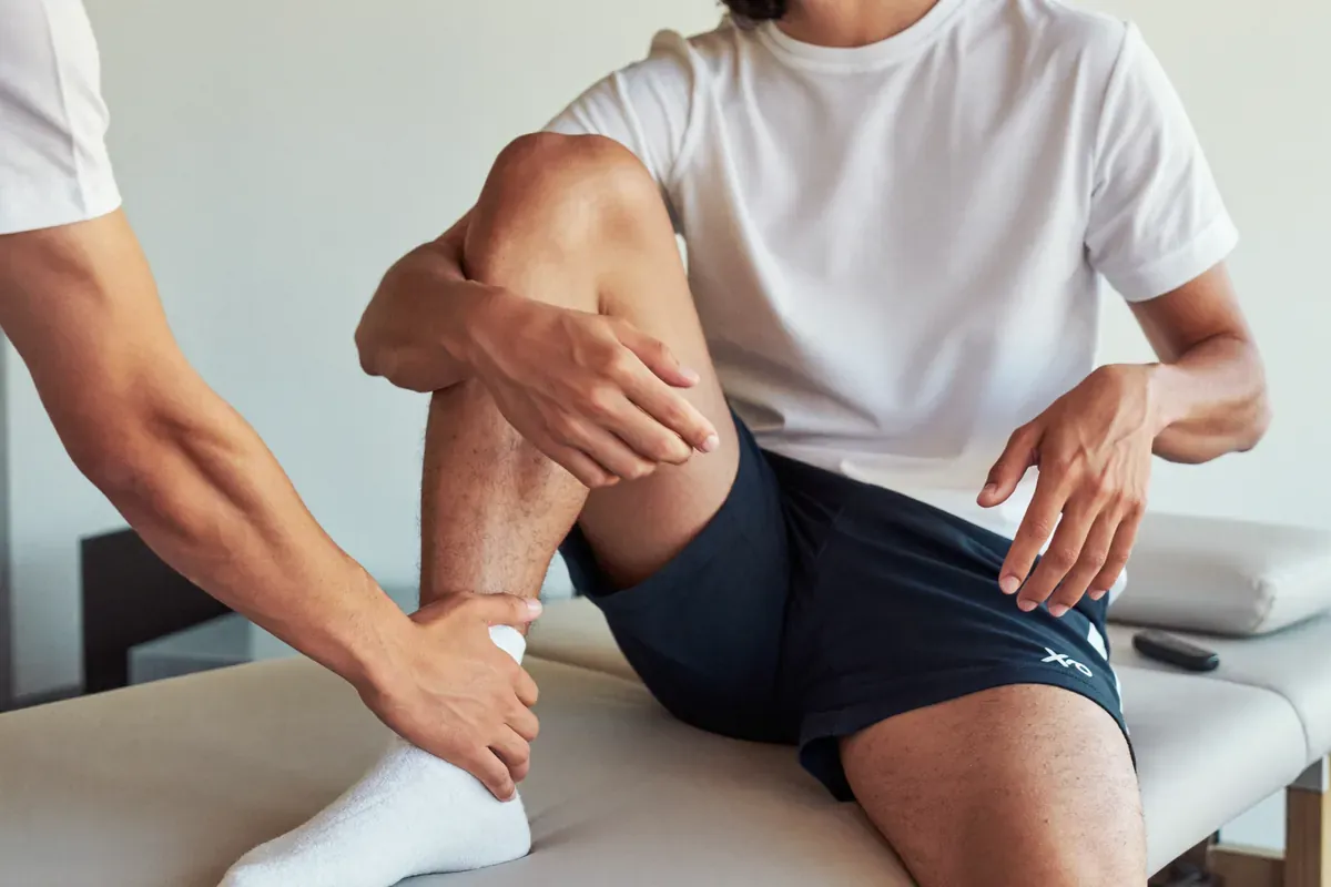 Clinician testing a patient's leg strength on an exam table